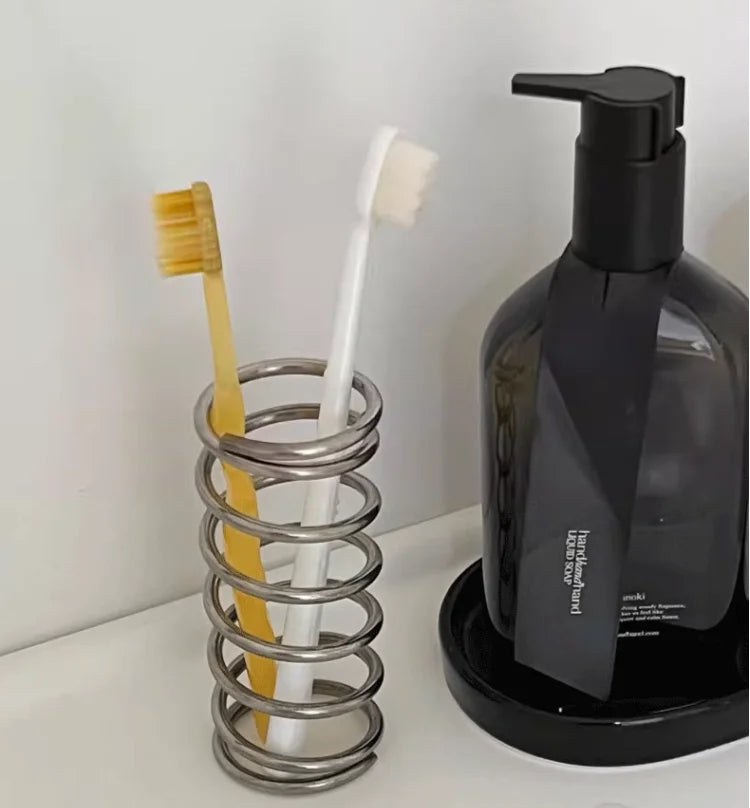 Stainless steel toothbrush holder with coil spiral design for organizing various items, including toothbrushes, makeup brushes, and office supplies. Sleek and functional bathroom or desktop accessory.