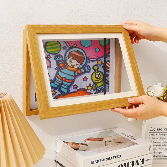 Harpy Frame featuring a wooden frame with an acrylic cover, available in three colors. Designed for A4-sized artworks, it includes a magnetic front for easy artwork changes and a white beveled mat for a polished presentation. Perfect for home decor enthusiasts looking to showcase children's artwork in a stylish and practical way.