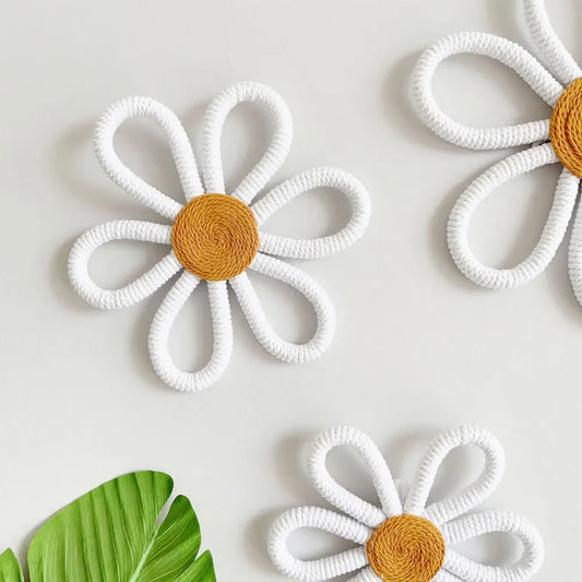 A display of Anna Wall Flowers made from macrame cotton rope, showcasing their intricate craftsmanship. Each flower is presented in a stunning white with a vibrant yellow center, adding a cheerful touch to the decor. Available in four different sizes, these wall flowers are perfect for a children's room, creating a playful and enchanting atmosphere. The lightweight design allows for easy installation on any wall, making it a delightful addition to kids' decor.