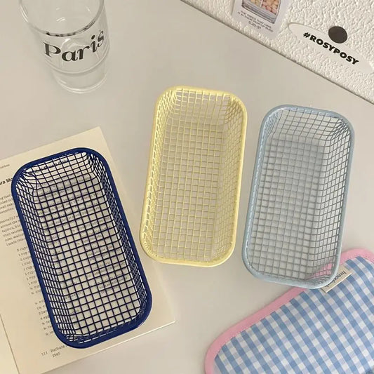 A small, versatile Elon Storage Basket displayed in a minimalist setting. The basket, made of durable metal, comes in butter yellow, sky blue, and navy. It is ideal for various uses, including organizing kitchen essentials, office supplies, or bath accessories. The sleek, utilitarian design complements modern and functional decor. The basket is shown in different color combinations, highlighting its mix-and-match capability for cohesive organization.