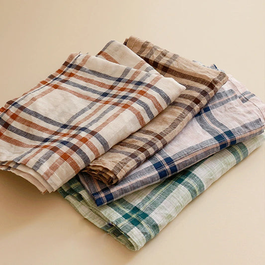 A set of large-format Veda Napkins measuring 40 x 60 cm, displayed in a classic plaid pattern with four neutral color options. The napkins are crafted from a durable cotton-linen blend, providing a textured, visually interesting look. Ideal for home décor enthusiasts, these versatile napkins add charm to any table setting.