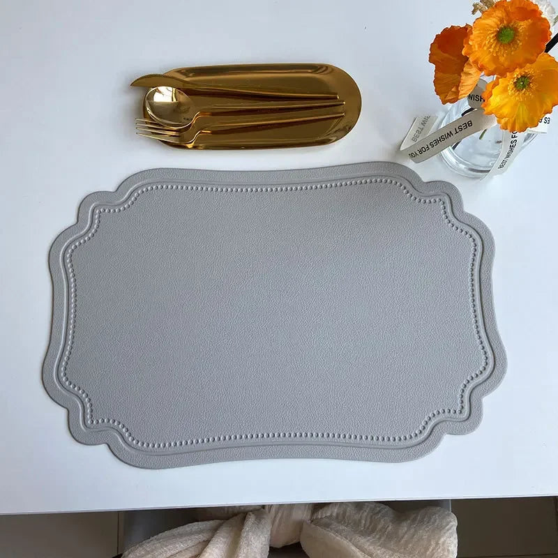 Zachary Placemat made from faux leather, featuring a sleek embossed design with curved edge detailing. The placemat measures 45 x 30 cm and is crafted from waterproof, oilproof PVC with a non-slip surface. Available in various colorways, it is ideal for home décor enthusiasts seeking both style and practicality for their dining table.