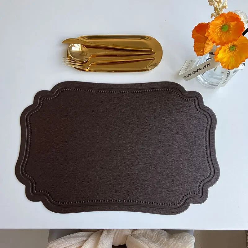 Zachary Placemat made from faux leather, featuring a sleek embossed design with curved edge detailing. The placemat measures 45 x 30 cm and is crafted from waterproof, oilproof PVC with a non-slip surface. Available in various colorways, it is ideal for home décor enthusiasts seeking both style and practicality for their dining table.