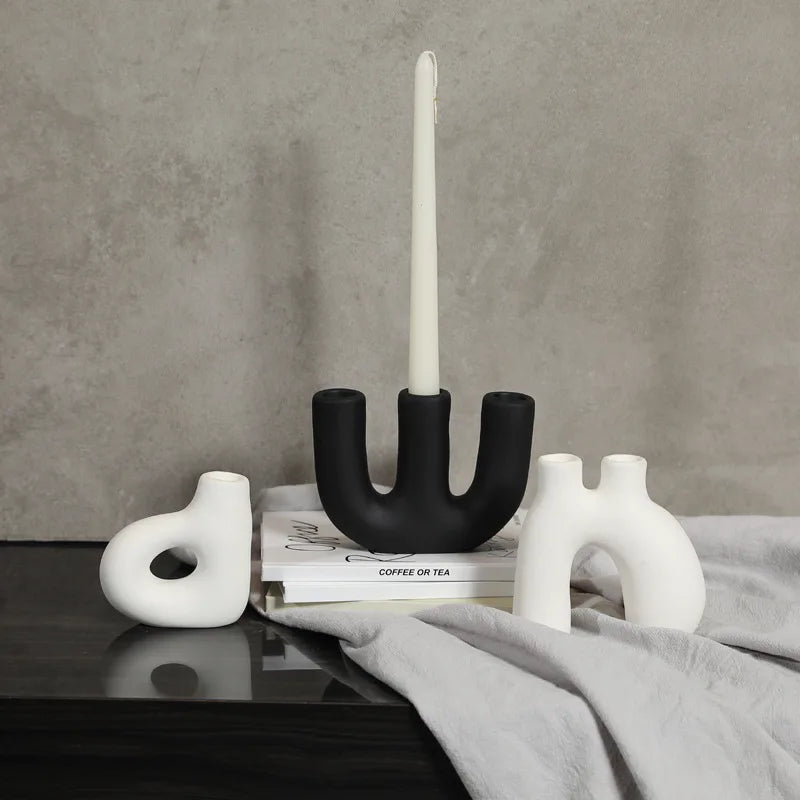 Reese Candle Holder collection - A modern display of ceramic candle holders in organic shapes, available in black and white colorways. The cool rounded shapes create a visually appealing design with four different variations. Elevate your space with these contemporary candle holders for a stylish and unique touch.