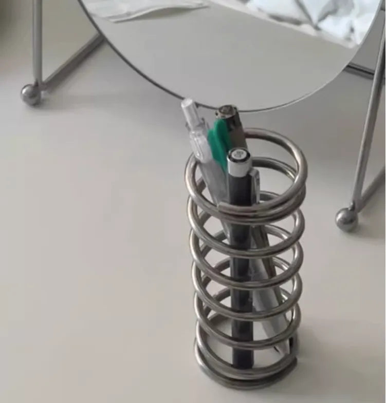 Stainless steel toothbrush holder with coil spiral design for organizing various items, including toothbrushes, makeup brushes, and office supplies. Sleek and functional bathroom or desktop accessory.