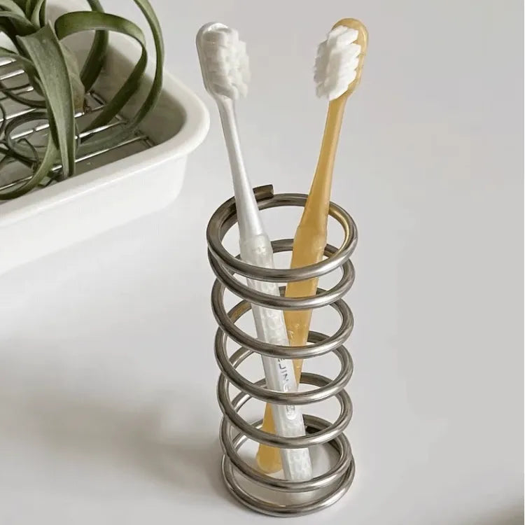 Stainless steel toothbrush holder with coil spiral design for organizing various items, including toothbrushes, makeup brushes, and office supplies. Sleek and functional bathroom or desktop accessory.