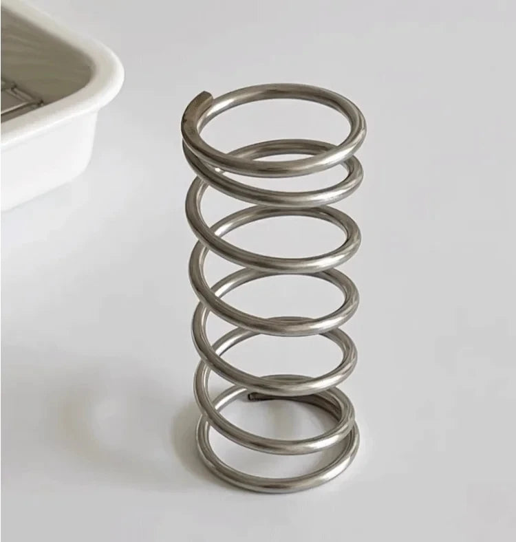 Stainless steel toothbrush holder with coil spiral design for organizing various items, including toothbrushes, makeup brushes, and office supplies. Sleek and functional bathroom or desktop accessory.