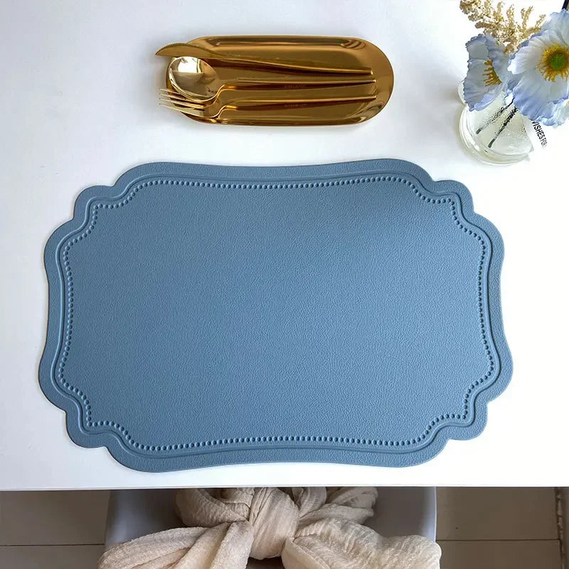 Zachary Placemat made from faux leather, featuring a sleek embossed design with curved edge detailing. The placemat measures 45 x 30 cm and is crafted from waterproof, oilproof PVC with a non-slip surface. Available in various colorways, it is ideal for home décor enthusiasts seeking both style and practicality for their dining table.