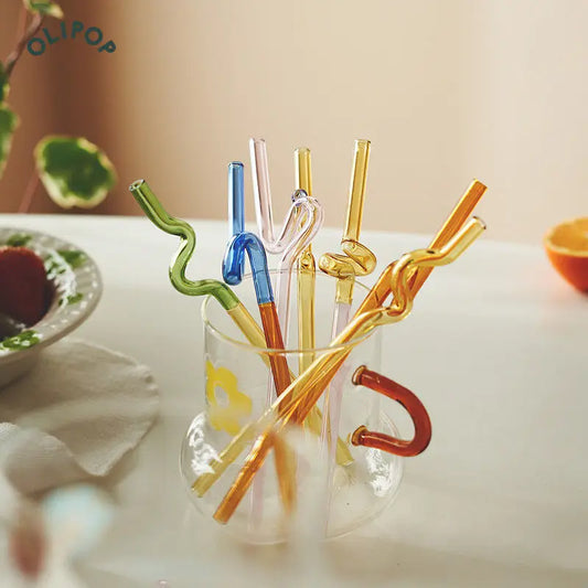 A colorful array of Xavier Glass Straws showcasing their two-tone design and variety of shapes. These straws feature vibrant hues like blues, greens, ambers, and pinks, perfect for adding a fun, stylish touch to any drink. Ideal for home décor enthusiasts, they are reusable and eco-friendly, making them a chic addition to any bar setup or dining table.